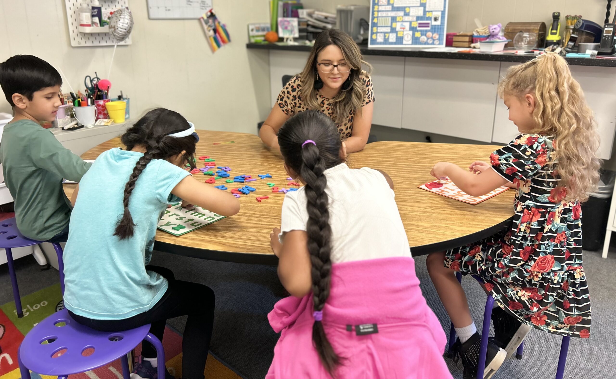 SNACS teacher in a K classroom with a group of students working on a project