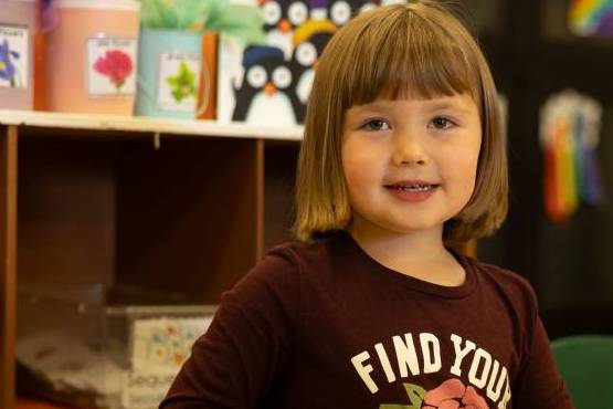 A SNACS student in their classroom, smiling at the camera, and ready to take on the school day!